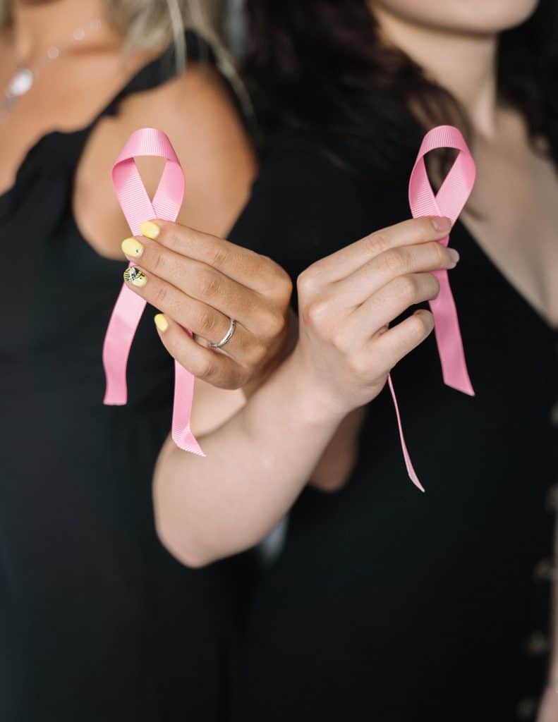Two women holding pink ribbons for breast cancer awareness
